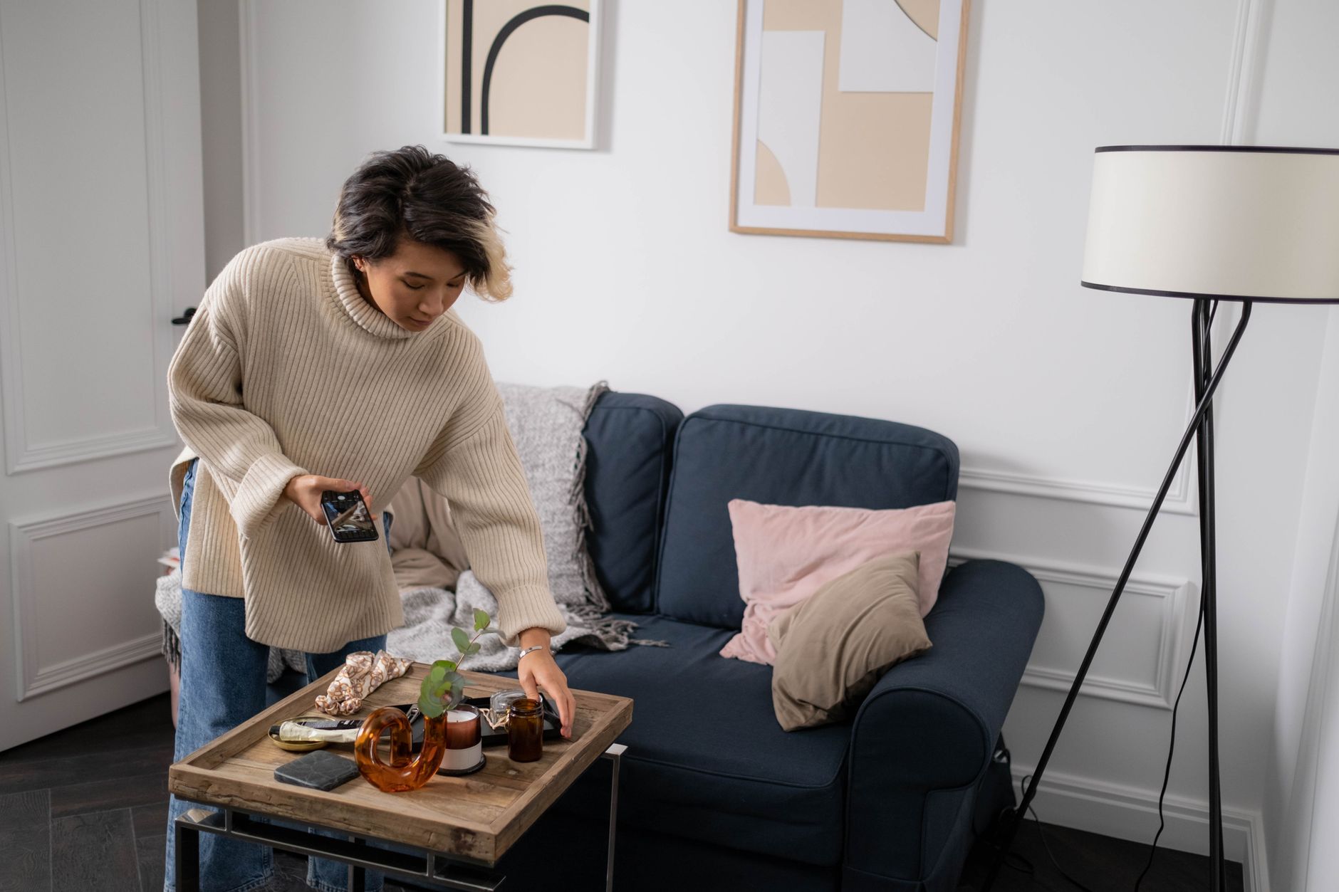 Woman arranging a decorative tray in a cozy living room setting with modern decor.
