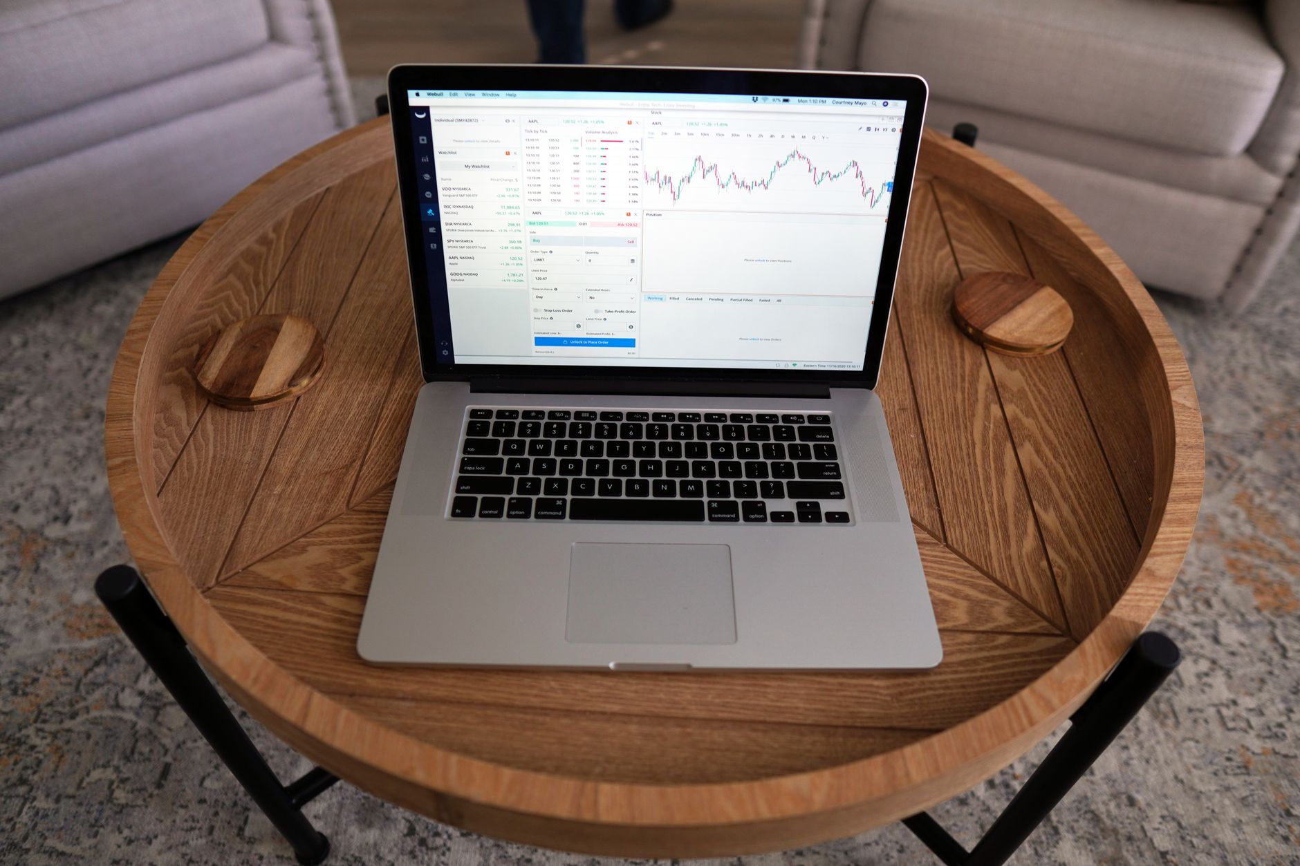 Close-up of a laptop displaying trading charts on a stylish wooden table, ideal for financial themes.