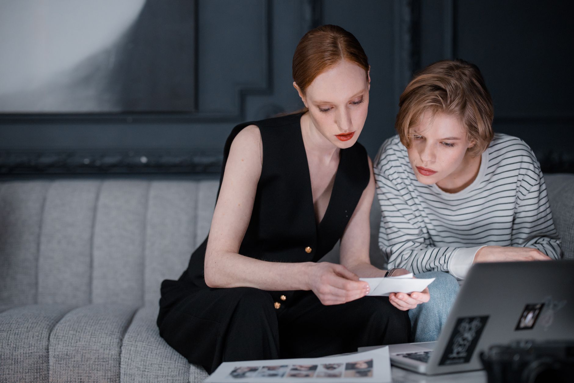 Two women reviewing photos and working together at a cozy indoor setting.