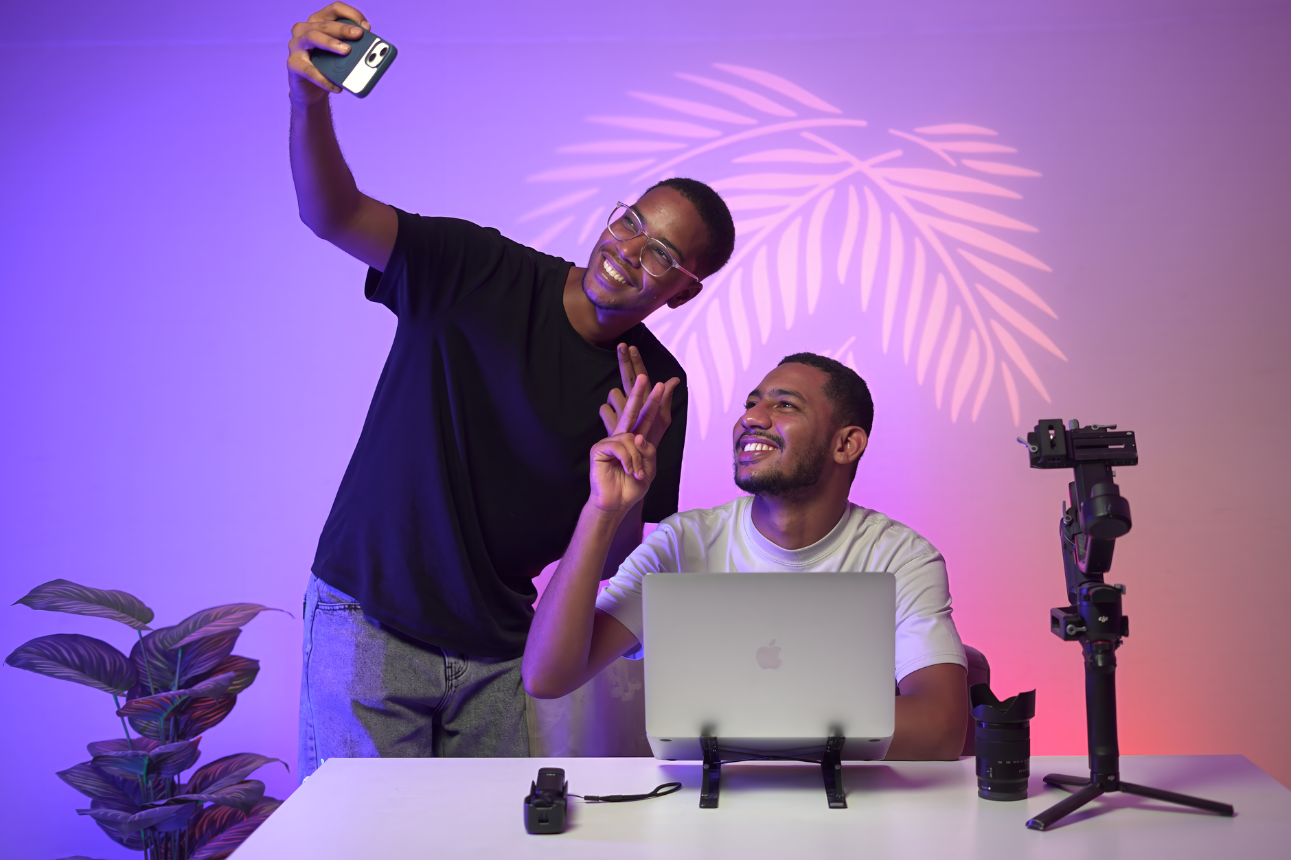 Two young adults taking a selfie in a modern studio with vibrant lighting and tech equipment.