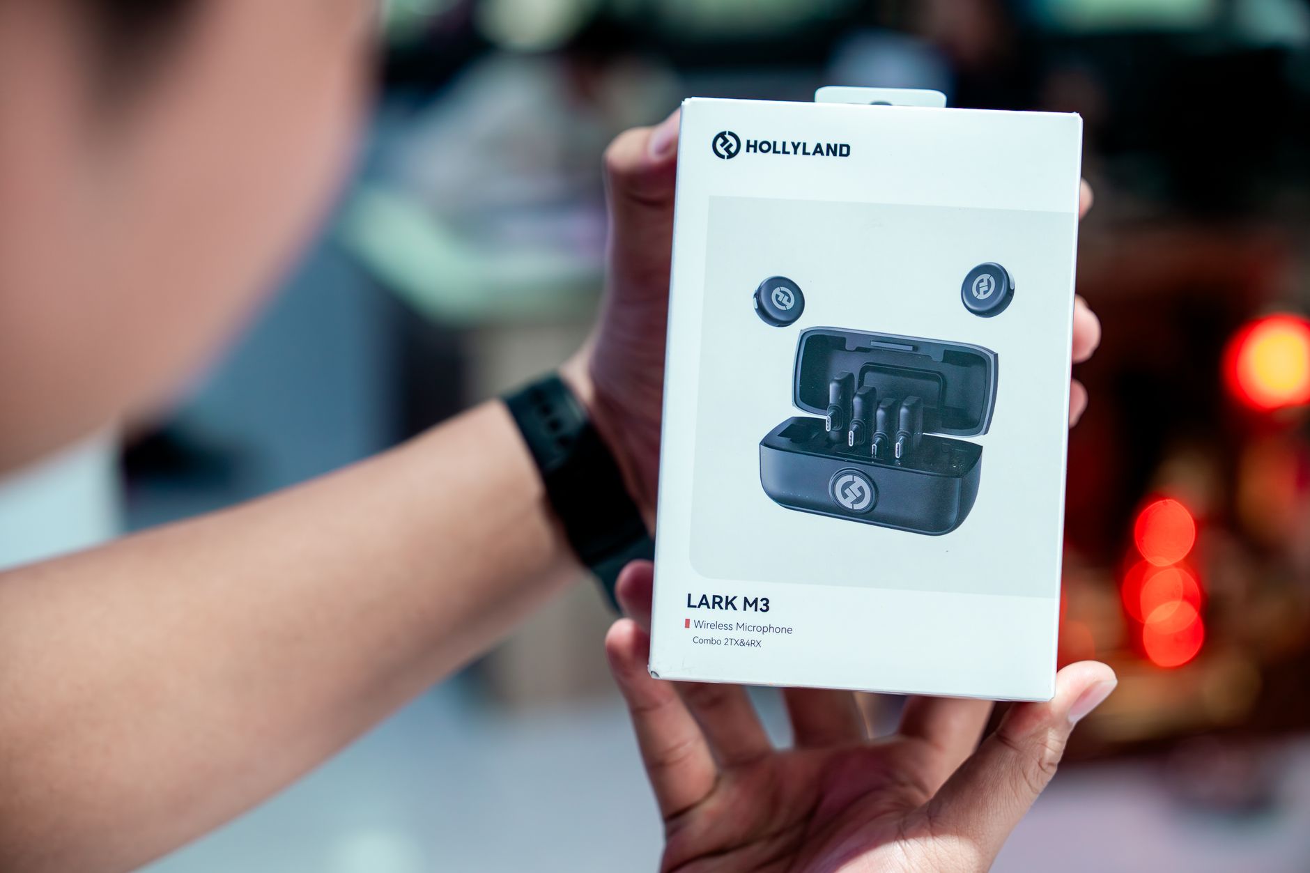 Person holding Hollyland Lark M3 wireless microphone package indoors.